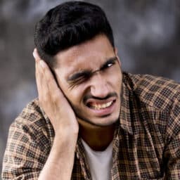 Man with ear pain holding his right ear.